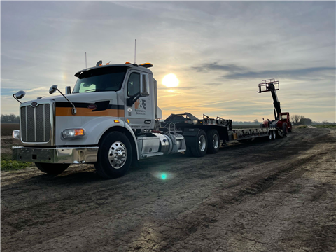 A flatbed trailers transporting a telehandler